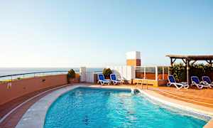 Utomhuspool med solstolar och havsutsikt. (AI-genererad text)