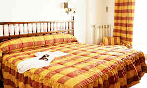 Ett hotellrum med en säng med gul och orange rutigt överkast. (AI-genererad text)