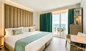 Hotellrum med stor säng samt balkong med havsutsikt. (AI-genererad text)