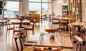 Moderna bord och stolar i trä i en restaurang med sjöutsikt. (AI-genererad text)