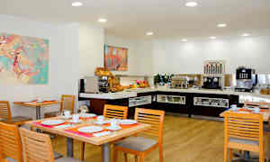 Matplats med dukade bord och buffé med kaffeautomat och frukostalternativ. (AI-genererad text)