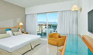 Ett hotellrum med en dubbelsäng, en fåtölj och en glasbord. (AI-genererad text)