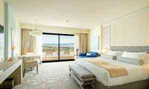 Ett hotellrum med en dubbelsäng, sittutrymme och en balkong med utsikt. (AI-genererad text)