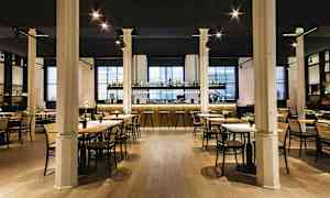 En elegant restaurang med bord och stolar samt en välbelyst bardisk i bakgrunden. (AI-genererad text)