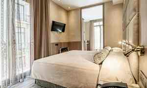 Ett hotellrum med en stor säng, ett väggmonterat tv och stora fönster med gardiner. (AI-genererad text)