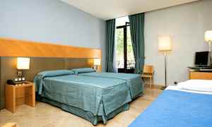 Hotellrum med två bäddar, gardiner och fönster. (AI-genererad text)