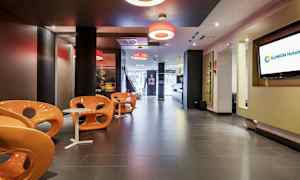 En modern hotellobby med orangea stolar och små vita bord. (AI-genererad text)