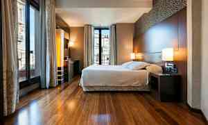 Ett modernt sovrum med en stor säng och stora fönster som släpper in mycket ljus. (AI-genererad text)