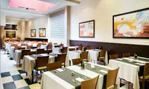 Matsal med dukade bord och upphängda tavlor på väggarna. (AI-genererad text)