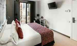 Ett modernt hotellrum med en stor säng, balkongdörrar och en skrivbordshörna. (AI-genererad text)