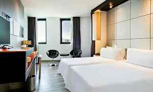 Ett elegant hotellrum med två enkelsängar, minimalistisk inredning och stora fönster som släpper in naturligt ljus. (AI-genererad text)