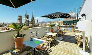 Takterrass med sittplatser och parasoller, med utsikt över stadens gamla byggnader och en barområde i bakgrunden. (AI-genererad text)