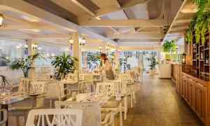 Interiör av en restaurang med trädetaljer, vita möbler och gröna växter. (AI-genererad text)