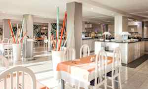 En restaurang med ljusa möbler, bord klädda med dukar, och dekorativa element som färgglada stånginstallationer. (AI-genererad text)