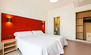 Hotellrum med två enkelsängar, en garderob och ett öppet badrum. (AI-genererad text)