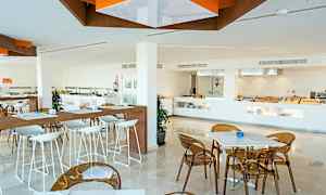 En modern restaurang med vita bord och stolar. En buffésektion syns i bakgrunden. (AI-genererad text)