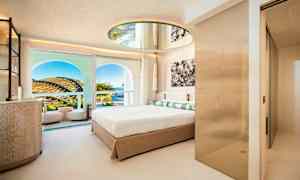 Ett modernt hotellrum med en stor säng, en rund spegel i taket och en balkong med utsikt över landskapet och himlen. (AI-genererad text)