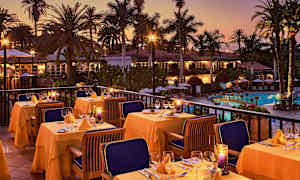 Uteservering med dukade bord, omgivna av palmer vid en pool under skymningen. (AI-genererad text)