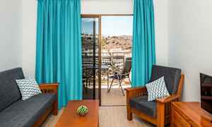 Vardagsrum med mörka möbler, blåa gardiner och utsikt från balkong. (AI-genererad text)