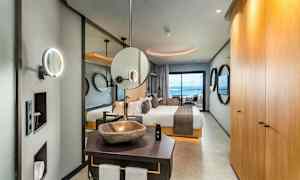 Interiör av ett elegant hotellrum med säng, badrum och utsikt mot havet. (AI-genererad text)