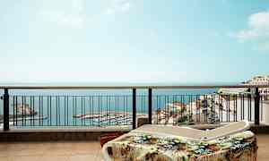 Solstolar på en terrass med utsikt över havet och en hamn. (AI-genererad text)