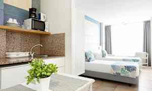 Interiör av ett hotellrum med ett pentry och två enkelsängar. (AI-genererad text)