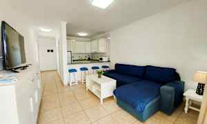 Ett vardagsrum med mörkblå soffa och öppet kök. (AI-genererad text)