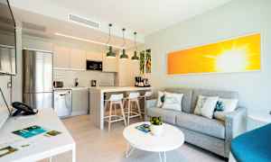 Interiör av ett modernt kök med integrerad vardagsrumsdel, grå soffa och färggrann konstverk. (AI-genererad text)