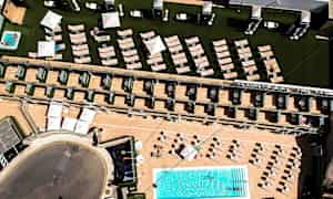 Flygfoto av hotellområde med pool, solstolar och parasoll. (AI-genererad text)