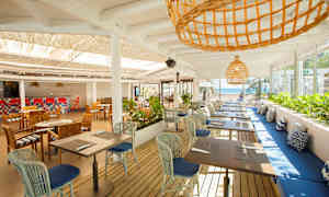 En öppen restaurang med bord och stolar samt havsutsikt. (AI-genererad text)