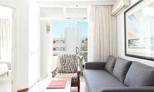 Vardagsrum med grå soffa, fåtölj och ett konstverk på väggen, med utsikt mot balkongen. (AI-genererad text)