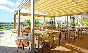 En terrass med flera bord och stolar under en takmarkis. (AI-genererad text)