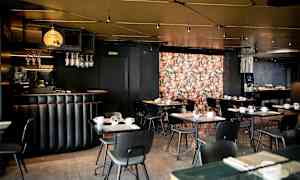 En restaurang med svart inredning och dekorerad vägg med blomtryck. (AI-genererad text)