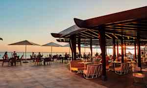 Öppen restaurangterrass med utsikt över havet vid solnedgång. (AI-genererad text)