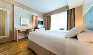 Ett hotellrum med en säng, skrivbord och fönster. (AI-genererad text)