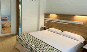 Hotellrum med en dubbelsäng och badrumsdörr i bakgrunden. (AI-genererad text)