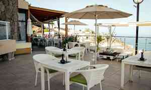 En terrass med bord och stolar samt utsikt över havet. (AI-genererad text)