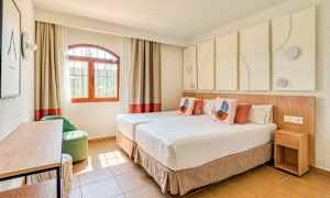 Ett ljust och modernt inrett hotellrum med två enkelsängar, en fönstervy och dekorativa element. (AI-genererad text)