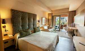 Ett hotellrum med en stor säng, soffa och skrivbord. Det finns även en balkong med utsikt. (AI-genererad text)