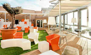 Utomhusområde med sittplatser, bord och ett träd planterat i en stor kruka. (AI-genererad text)