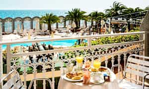 Utsikt från en balkong med frukostdukning mot poolområde och havet. (AI-genererad text)