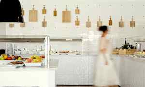 Bild av ett bufféområde med frukt och sallad, en person går förbi. (AI-genererad text)