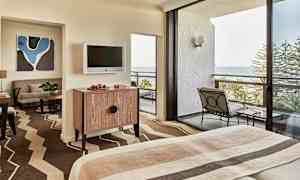 Hotellrum med säng, möbler och balkong med havsutsikt. (AI-genererad text)