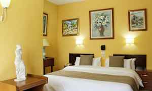 Ett hotellrum med en dubbelsäng, dekorerade väggar med målningar och en liten staty på en möbel. (AI-genererad text)