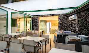 Matsalsområde med bord och stolar samt en bufféuppställning bredvid en vägg av sten. (AI-genererad text)