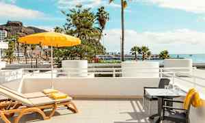 Solstolar och bord med utsikt över havet och palmer. (AI-genererad text)