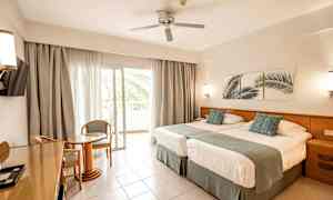 Hotellrum med två sängar, sittgrupp och balkong. (AI-genererad text)