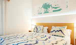 Säng med två kuddar och ett täcke i ett ljust rum. (AI-genererad text)