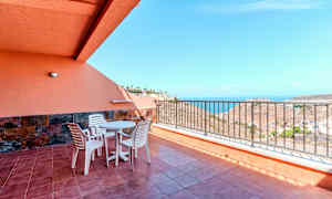 Terrass med bord, stolar och räcke, samt havsutsikt. (AI-genererad text)
