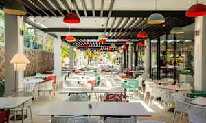 En modern restaurang med många färgglada stolar och bord. (AI-genererad text)